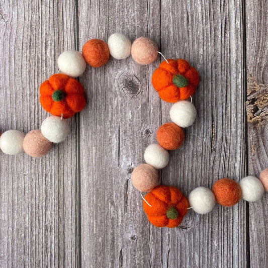 Decorative garland with felt pumpkins and balls on a wooden surface