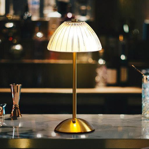 Gold table lamp with pleated shade on a bar counter with blurred bar background