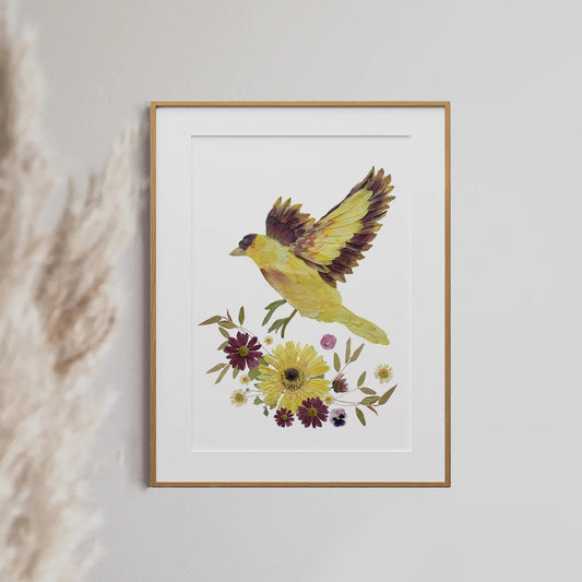 Framed artwork of a yellow bird and flowers on a white wall.