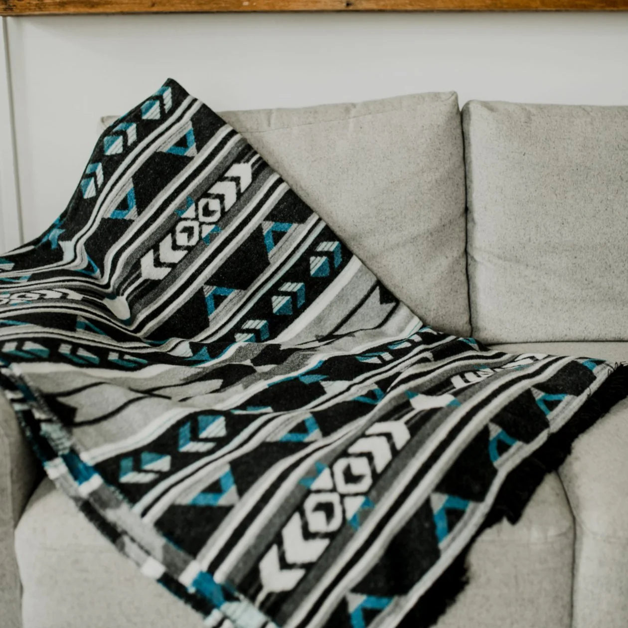 Patterned blanket draped over a gray sofa