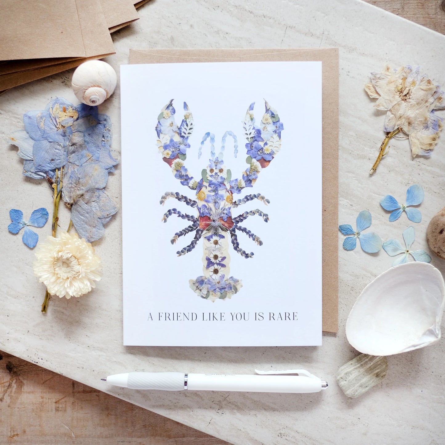 Greeting card with floral lobster design and text on a wooden surface with decorative elements.