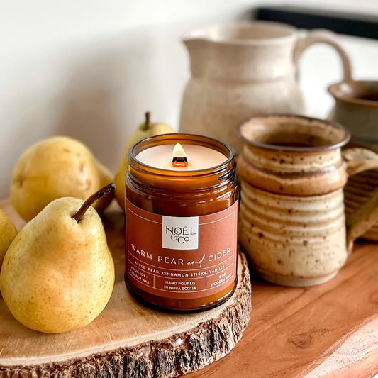 Jar candle with pear and ceramic items on a wooden surface