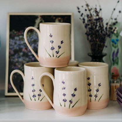 Stack of ceramic mugs with floral design on a shelf