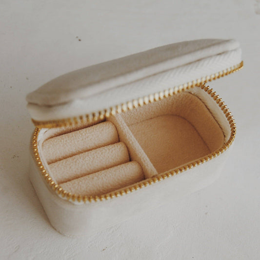 Beige travel jewelry case with gold zipper on a white background