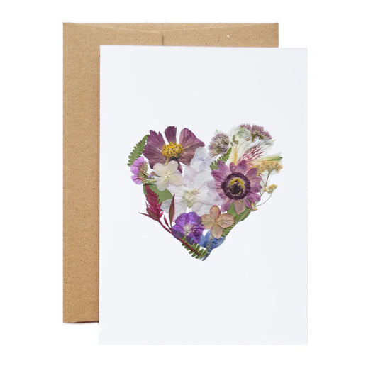 Greeting card with a heart-shaped arrangement of pressed flowers on a white background